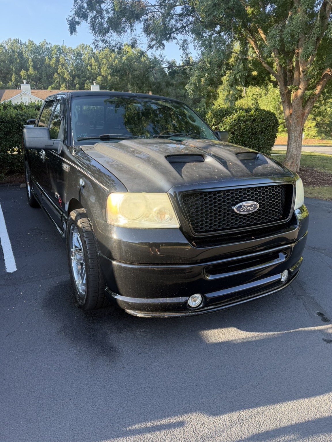 Black Ford F-150 before detailing, showing dust and cloudy headlights