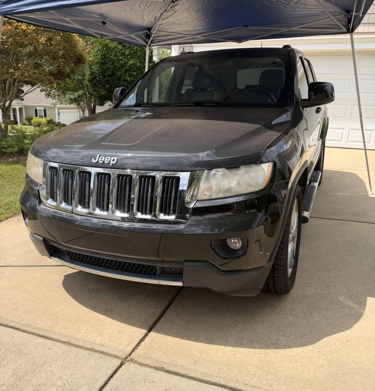 Black Jeep Grand Cherokee before detailing, with dust across the hood