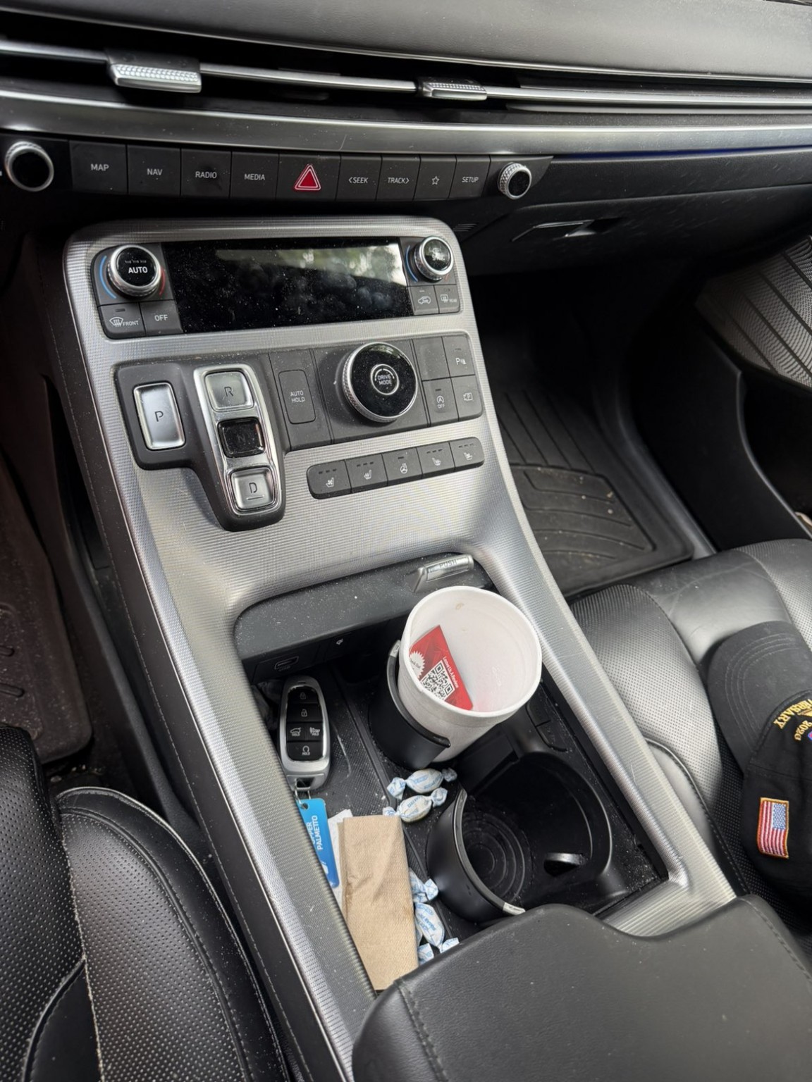Hyundai Palisade center console before detailing, with dust and items in the cup holders