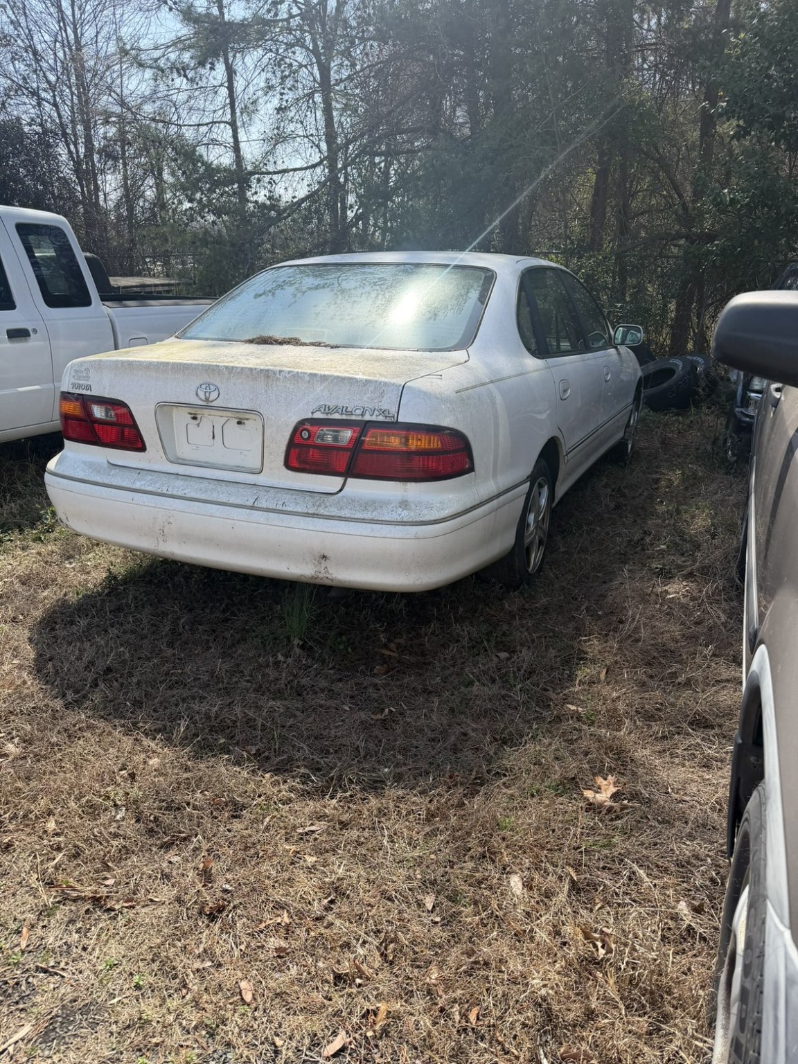 White Toyota Avalon before detailing, with dirt on the trunk and rear bumper